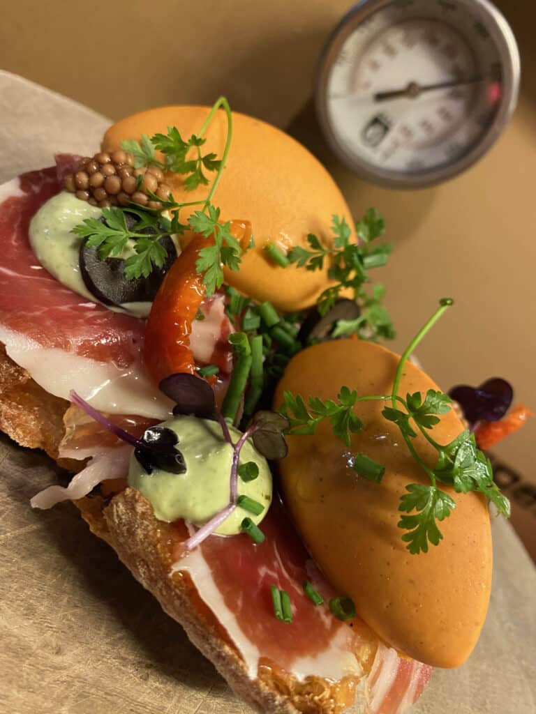 Broodje met rauwe ham, gerookte vis, avocadocrème en kervel, bereid bij Gastro Henri.