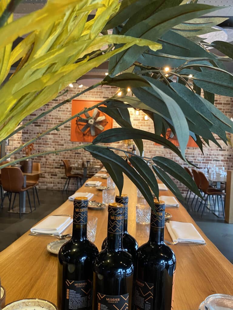 Gedekte lange tafel met flessen rode wijn in het interieur van Gastro Henri in Roeselare.