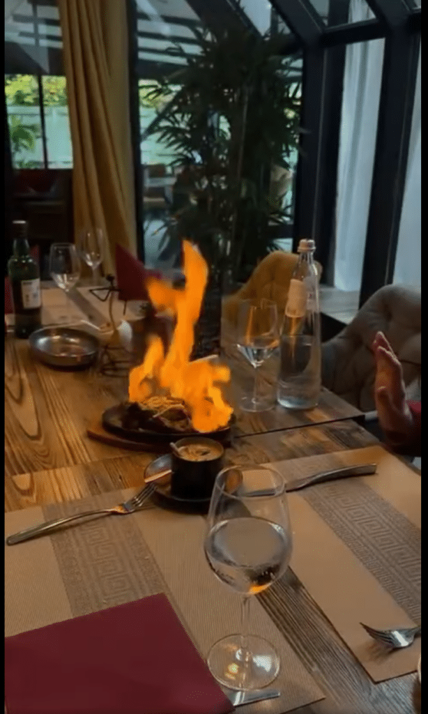 Geflambeerd gerecht aan tafel in de veranda van Lychee Garden.