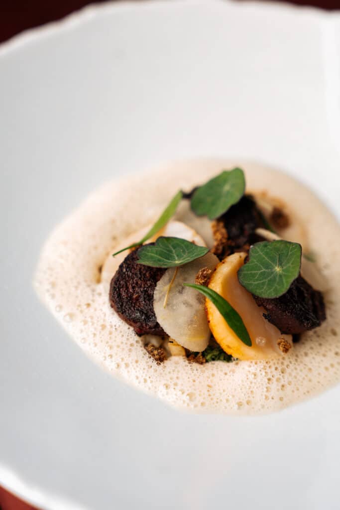 Gerecht bij Flambée: gelakt vlees met peer, Oost-Indische kers en een romige schuimsaus.