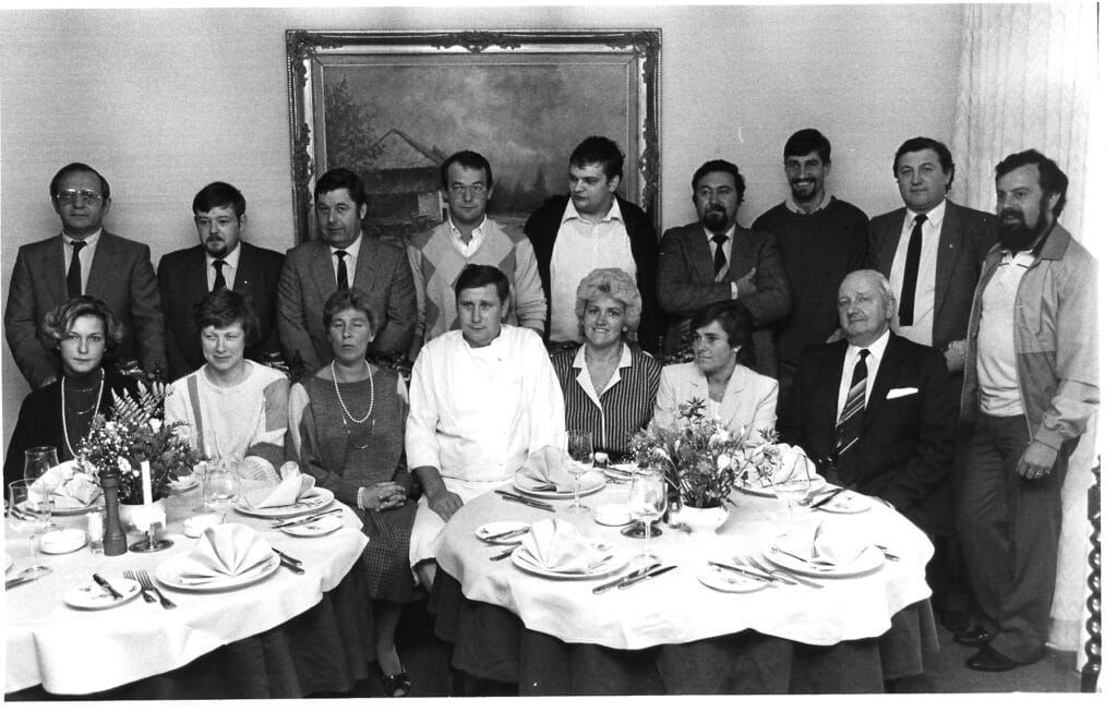 Zwart-witfoto van de leden van GastroRSL rond een gedekte tafel, 2009.