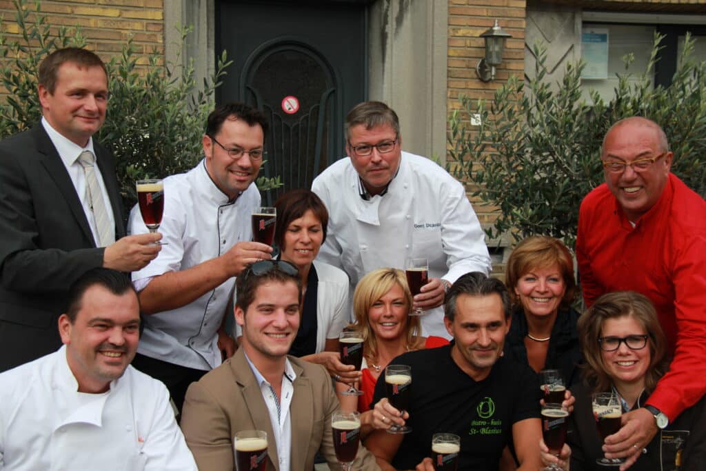 De leden van GastroRSL klinken met een glas bier bij een restaurantingang.